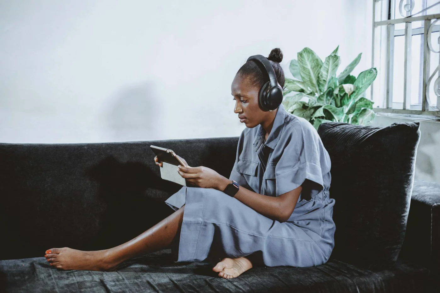 Woman relaxing on a sofa with headphones and tablet while reading about flow neuroscience clinical trials