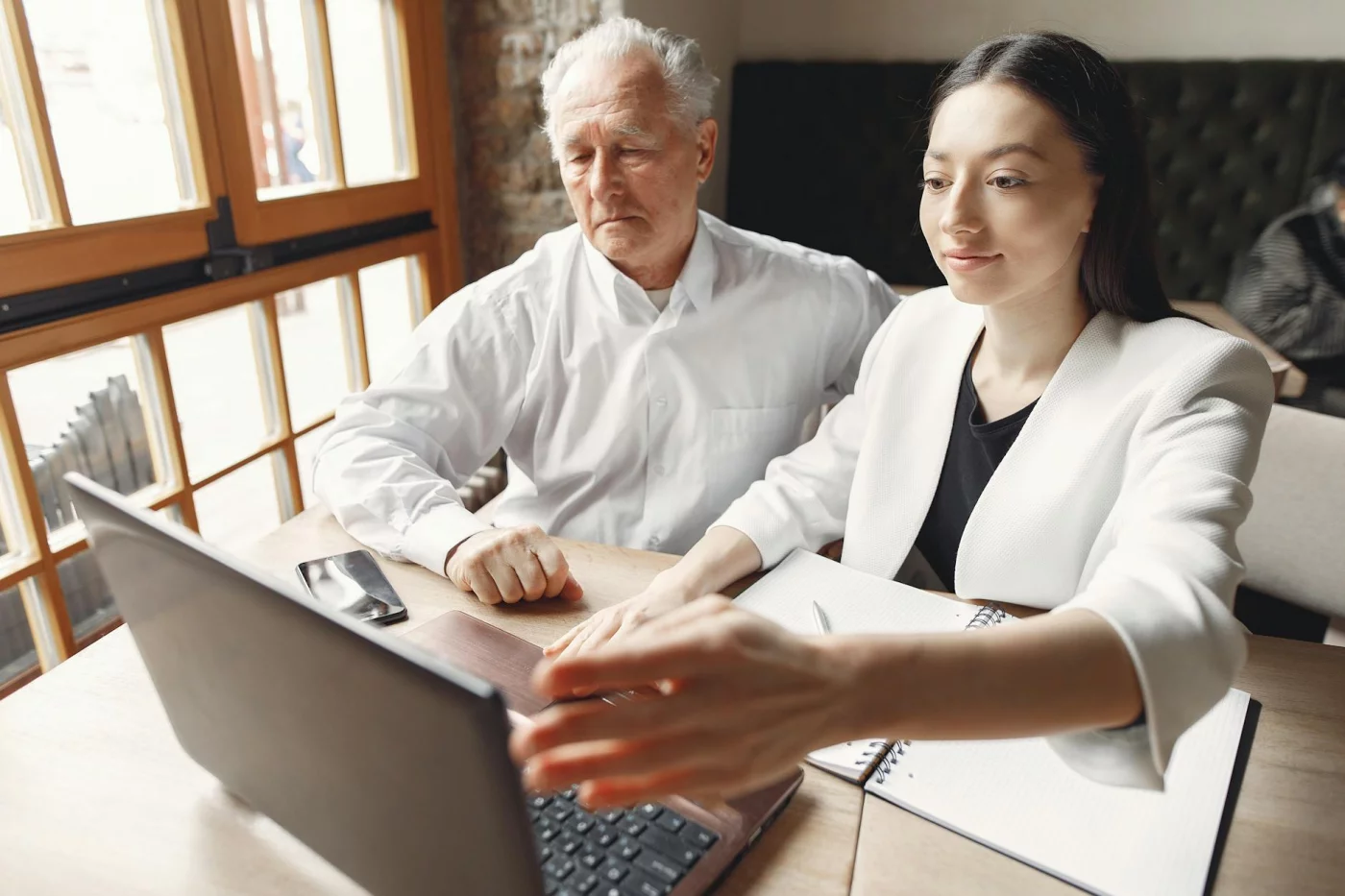 Senior man and woman using a laptop and notes to plan free online courses for seniors in a bright workspace