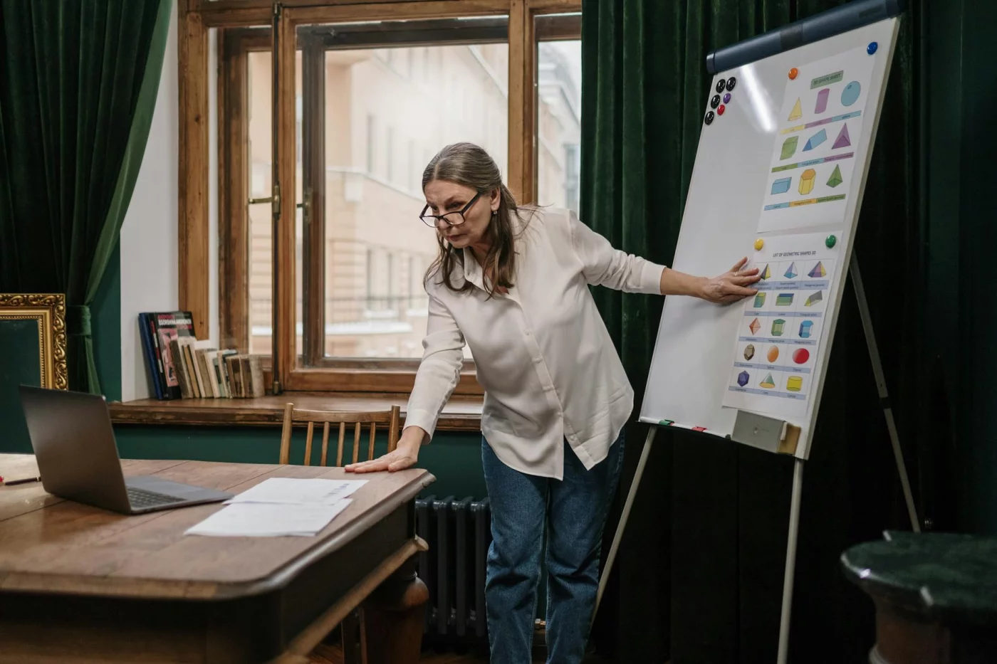 Senior woman teaching geometry with a flip chart and laptop, illustrating free online courses for seniors
