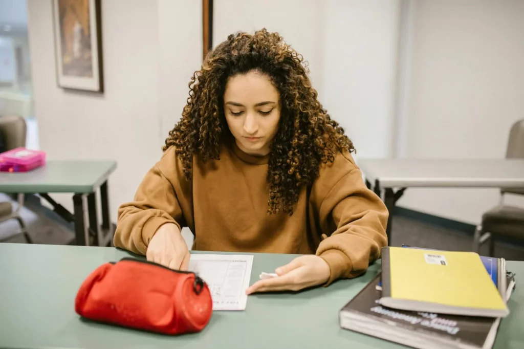 College student reviewing books and notes while learning how to create a study guide for an exam