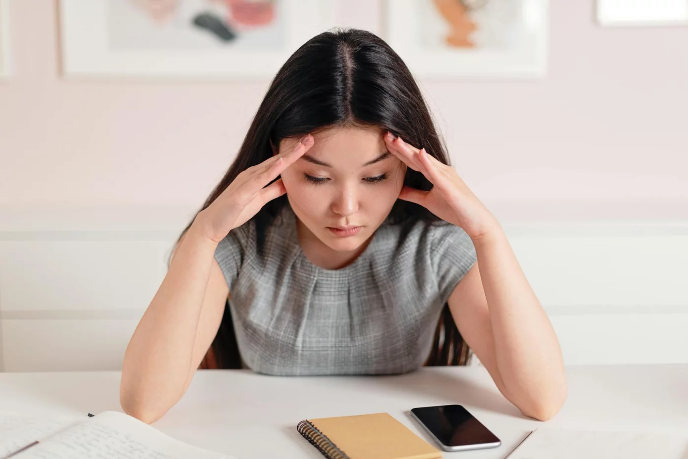 Stressed woman at her desk with a headache, illustrating how to improve focus while studying under pressure