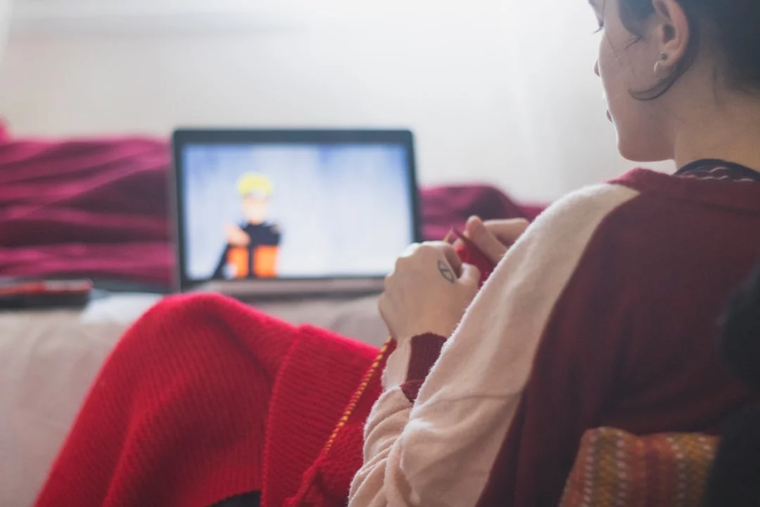 Woman in red sweater watching a show, demonstrating how to use TV shows to learn a language