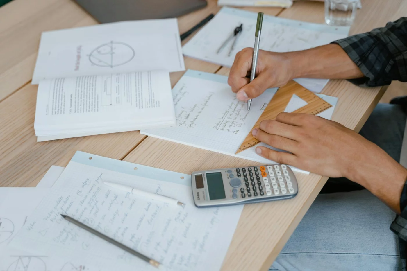 Student reviewing math work after thinking, "i did bad on a test i studied hard for," using a calculator at a desk