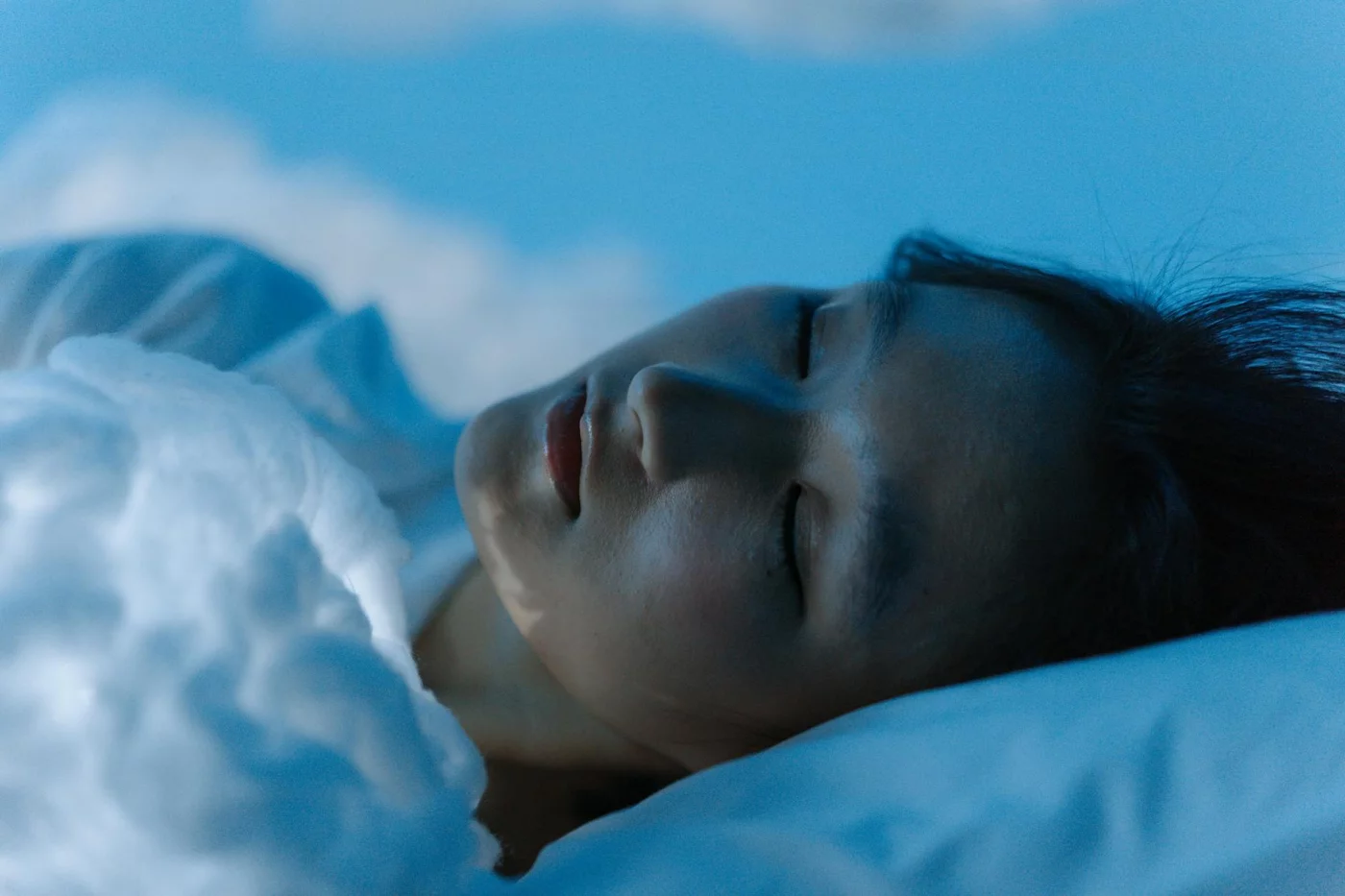 Woman sleeping peacefully on a white pillow, illustrating rem sleep and memory consolidation across the night