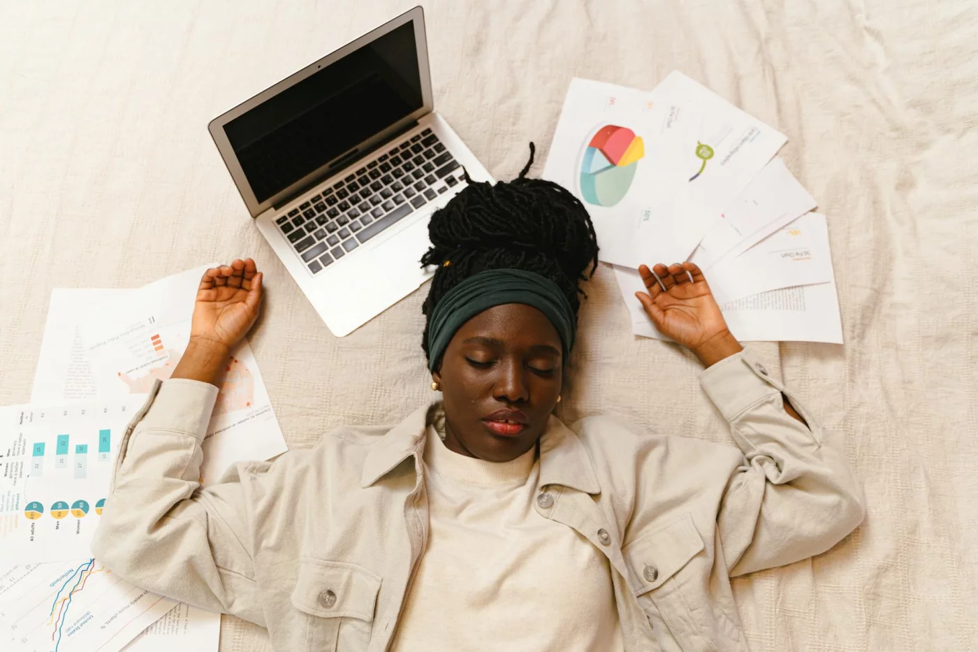 Tired woman resting by a laptop and papers, illustrating rem sleep and memory consolidation after studying