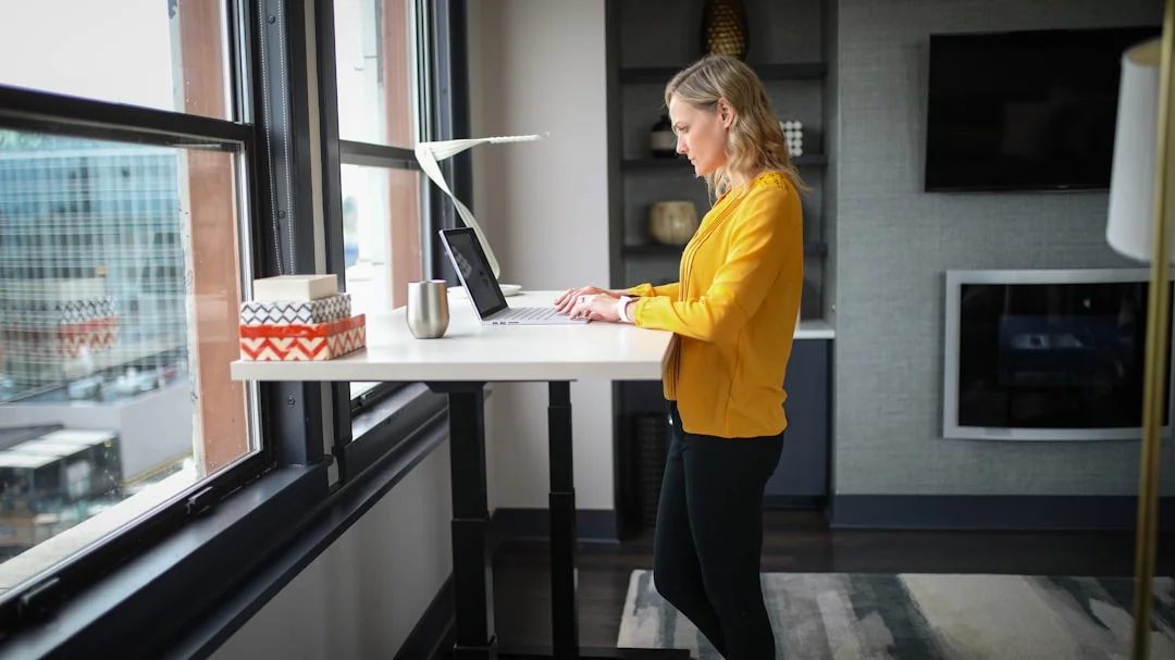 Woman beside a white table demonstrating what is the 20 8 2 rule in 5 practical workstation setup steps