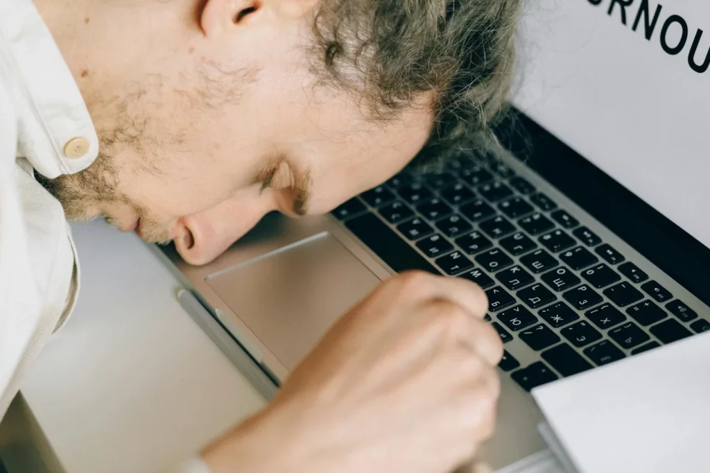 Exhausted employee resting on a laptop at work, illustrating what to do when emotionally exhausted