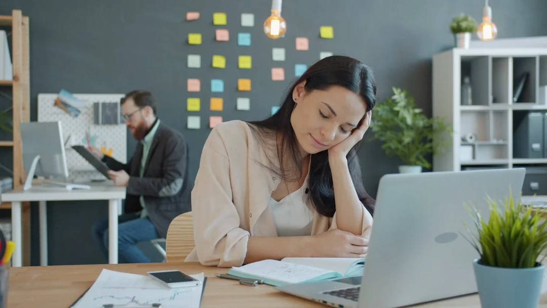Woman resting her head on her hand at a desk, reflecting on what to do when emotionally exhausted at work
