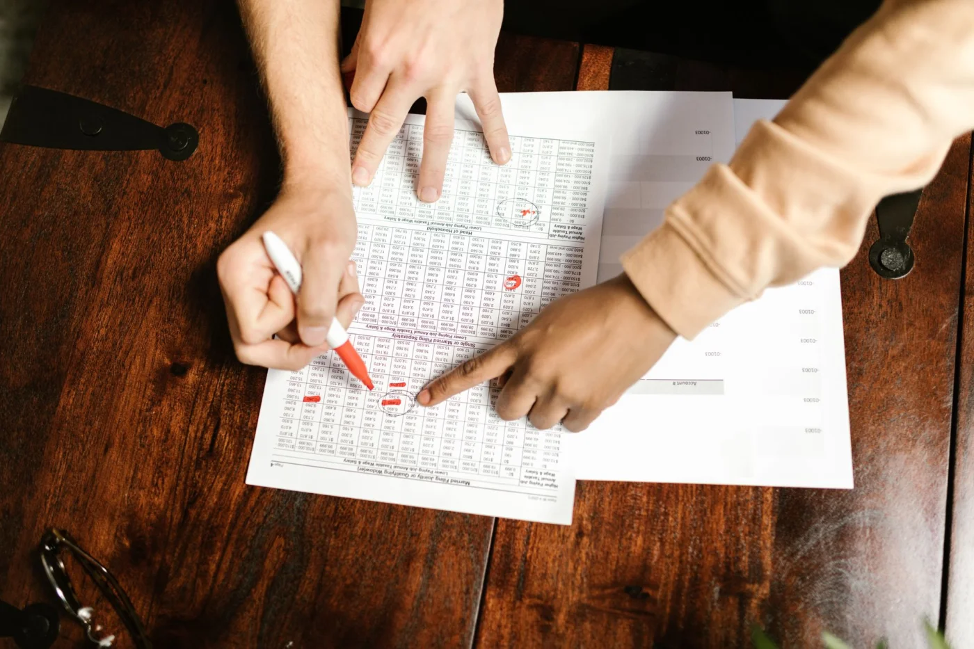 Exam Review Error Ledger for Accounting Errors and Corrections Hands marking financial documents with red pen to review accounting errors and corrections