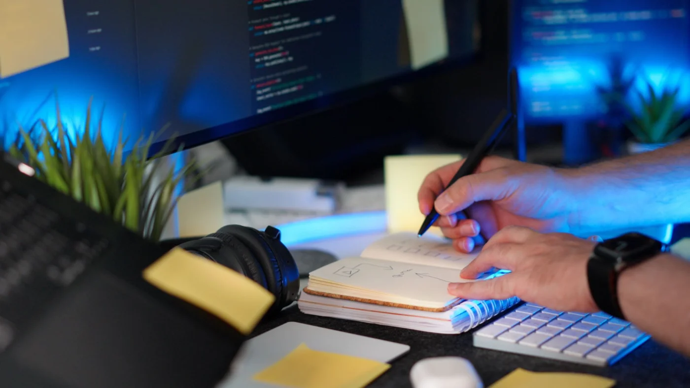 How to Use AI Productivity Apps Without Hurting Deep Learning Person planning a software project with handwritten notes and ai productivity apps on a monitor in a modern workspace