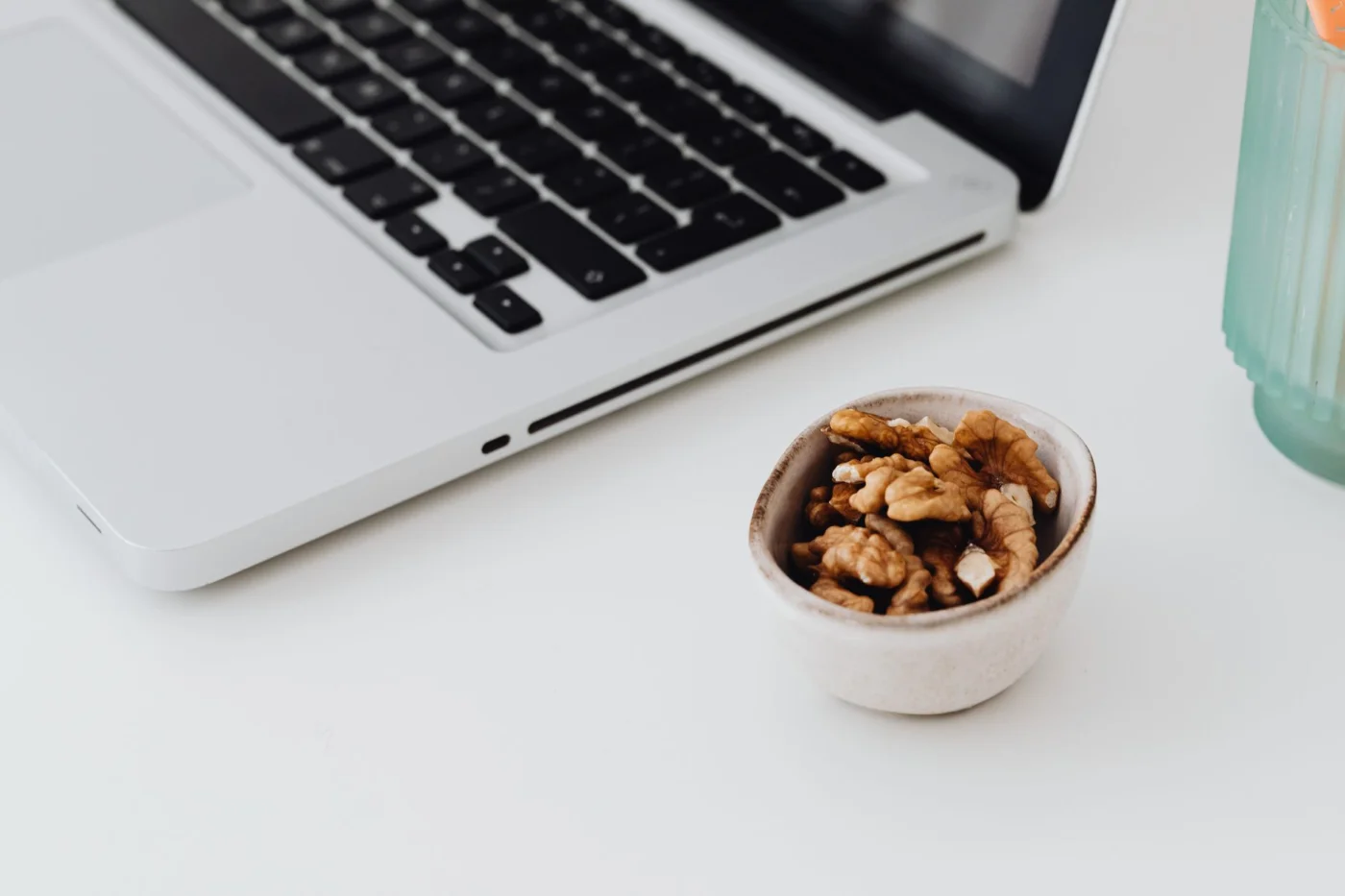 How to Improve Memory, Focus, and Learning With Science-Backed Habits Minimal desk with laptop and walnuts, one of the best foods for memory and focus, for a healthy work snack
